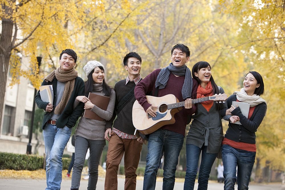 Chinese College Students Walking And Playing Guitar On Campus In Autumn